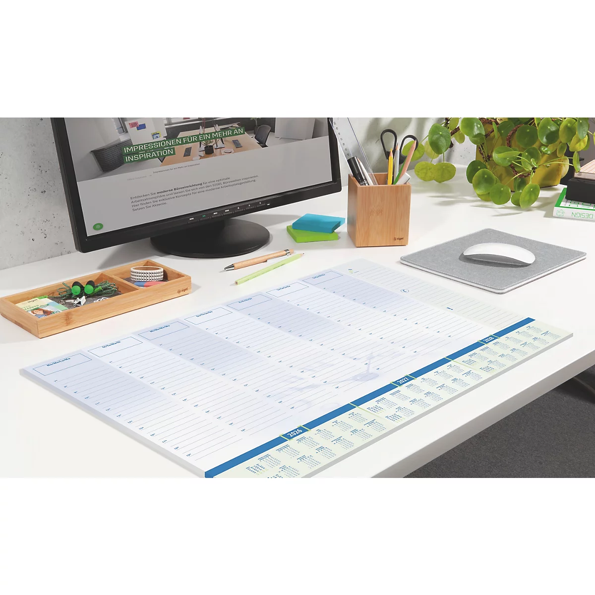 Bureau met weekplanner, computer, pennenhouder, muismat en potplant.