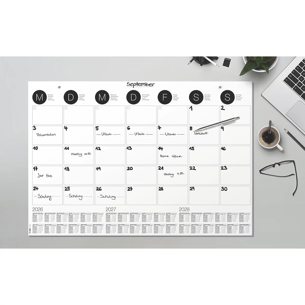 Een bureaudooskalender met de maand september. Afspraken die erop genoteerd staan. Daarnaast een pen, laptop, bril en koffie.