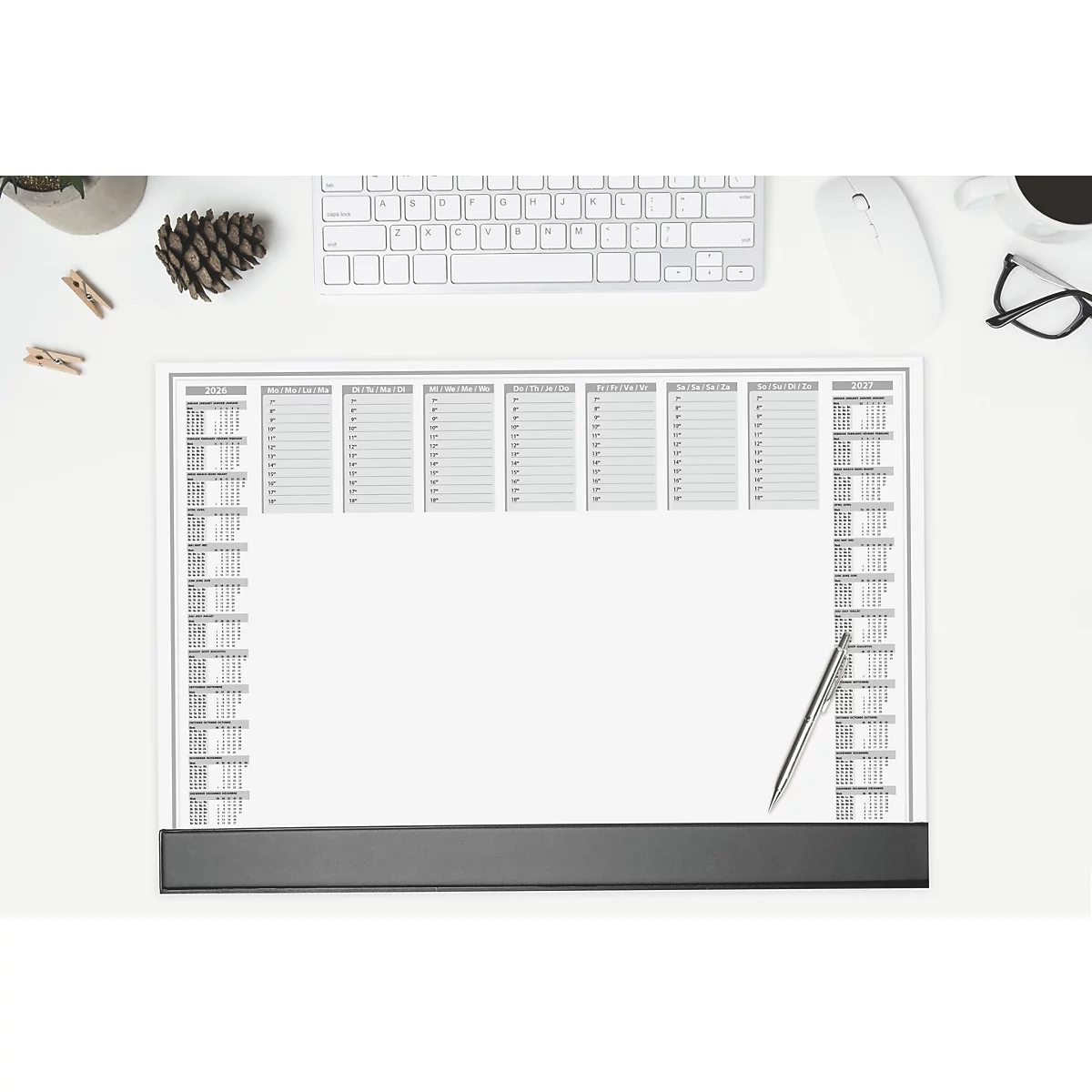 Bovenaanzicht van een wit bureau. Op de tafel liggen een kalender, toetsenbord, muis, bril, koffiekopje, pennen en decoratie.