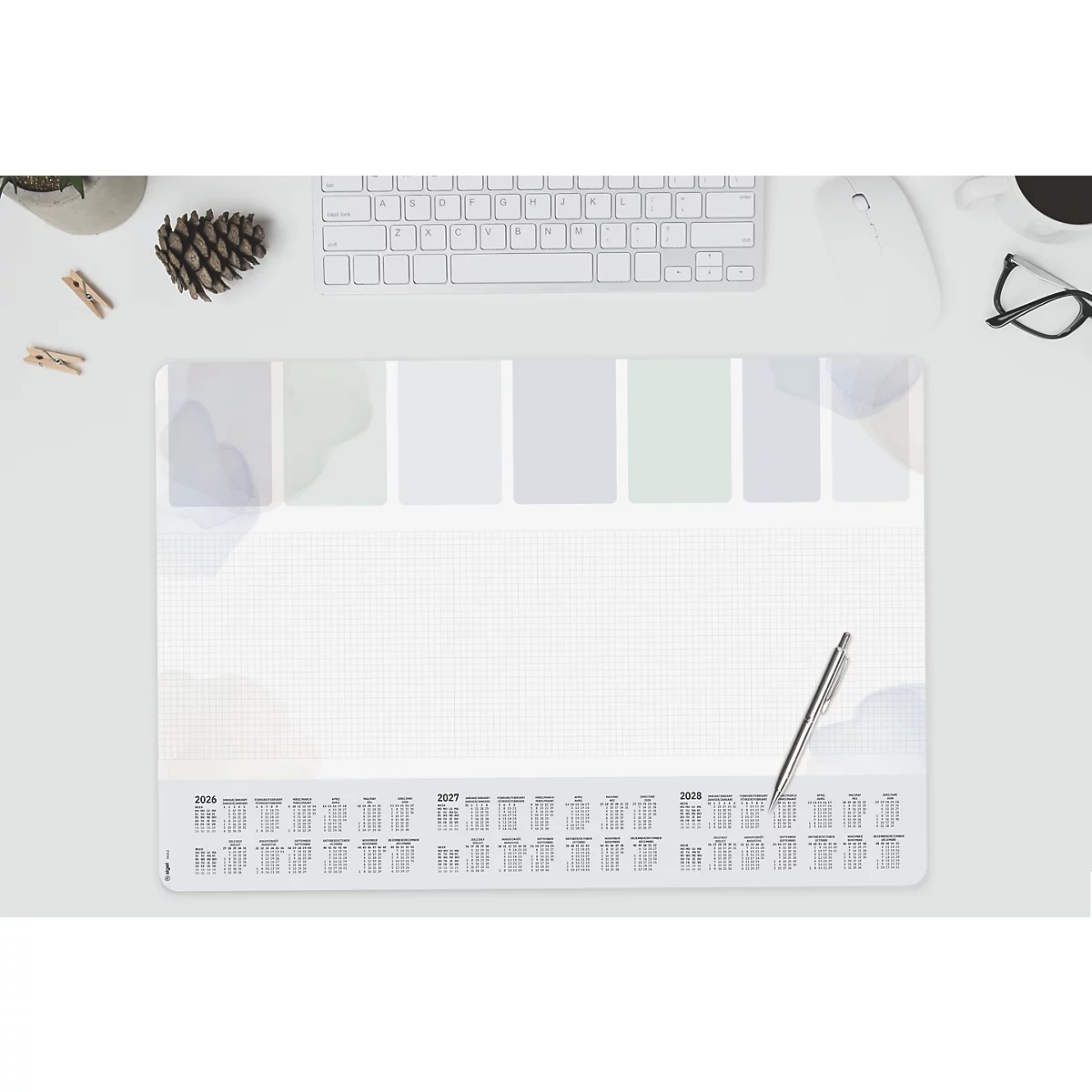 Bureaumat met kalender en pen. Toetsenbord, muis, bril, dennenappel en plant erboven.