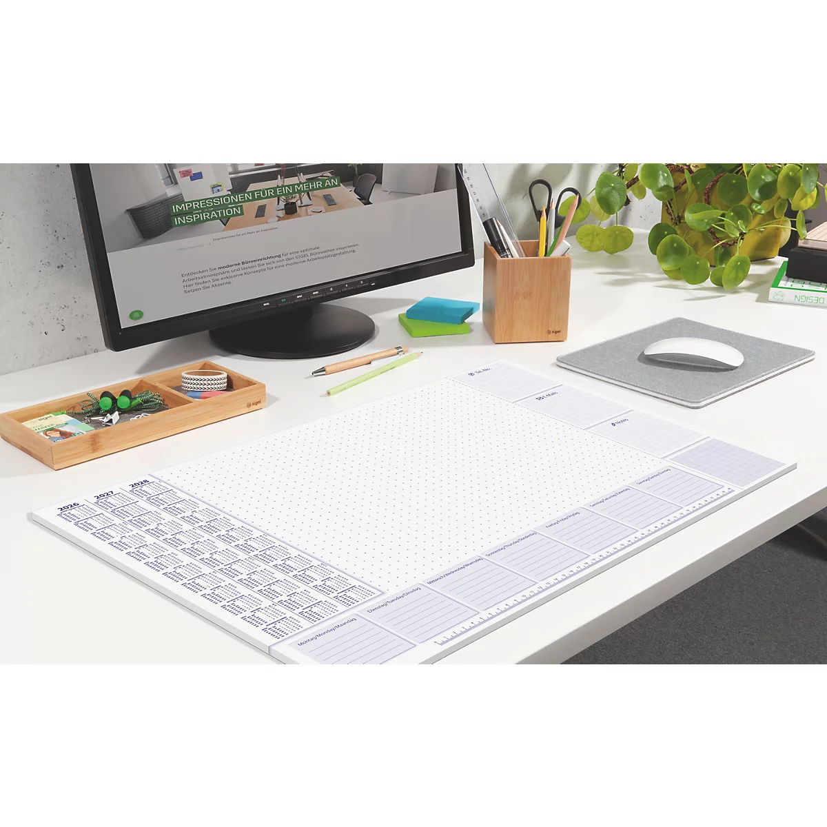 Bureau met muismat, notities, scherm en bamboe penhouder.