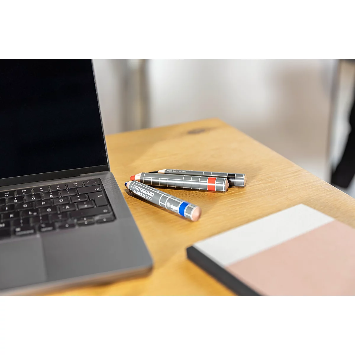 Plusieurs marqueurs de tableau blanc colorés dans un récipient en bois. Les marqueurs indiquent "Whiteboard Marker Eco".