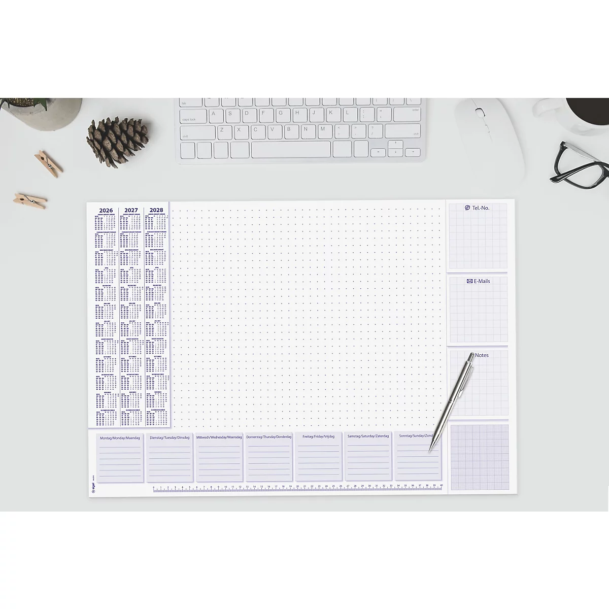 Tapis de bureau gris clair avec calendrier, blocs quadrillés et un stylo. Clavier et lunettes également sur la table.