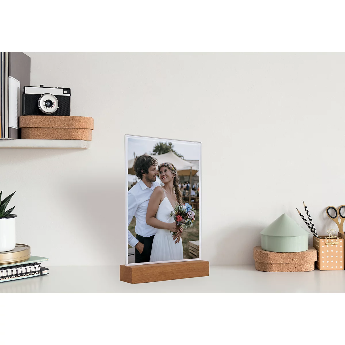 Wedding photo in a wooden frame. On a desk with decor and a camera.