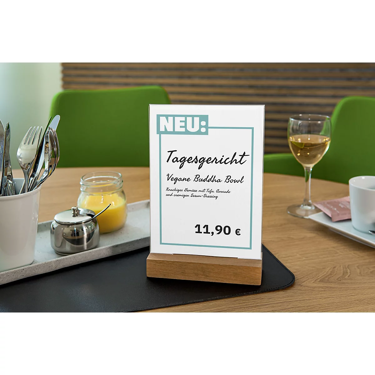 Daily special: vegan Buddha bowl, price 11,90€, on table card. Next to it glass of wine, cutlery, glass with sauce.