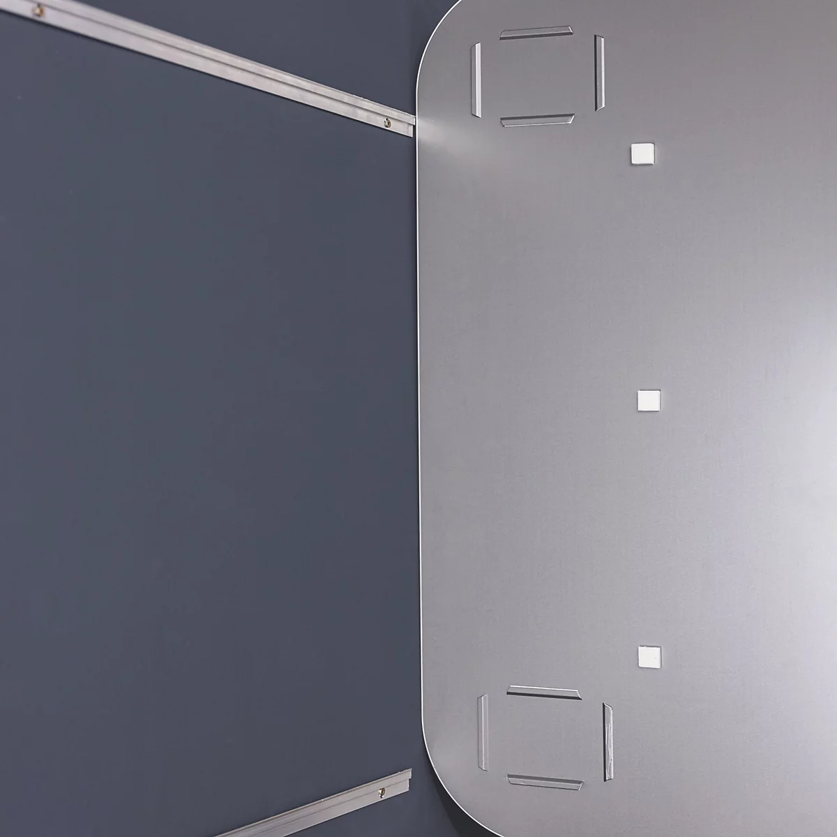 Gros plan d'une plaque de métal grise avec des découpes rectangulaires et de petites élévations carrées.