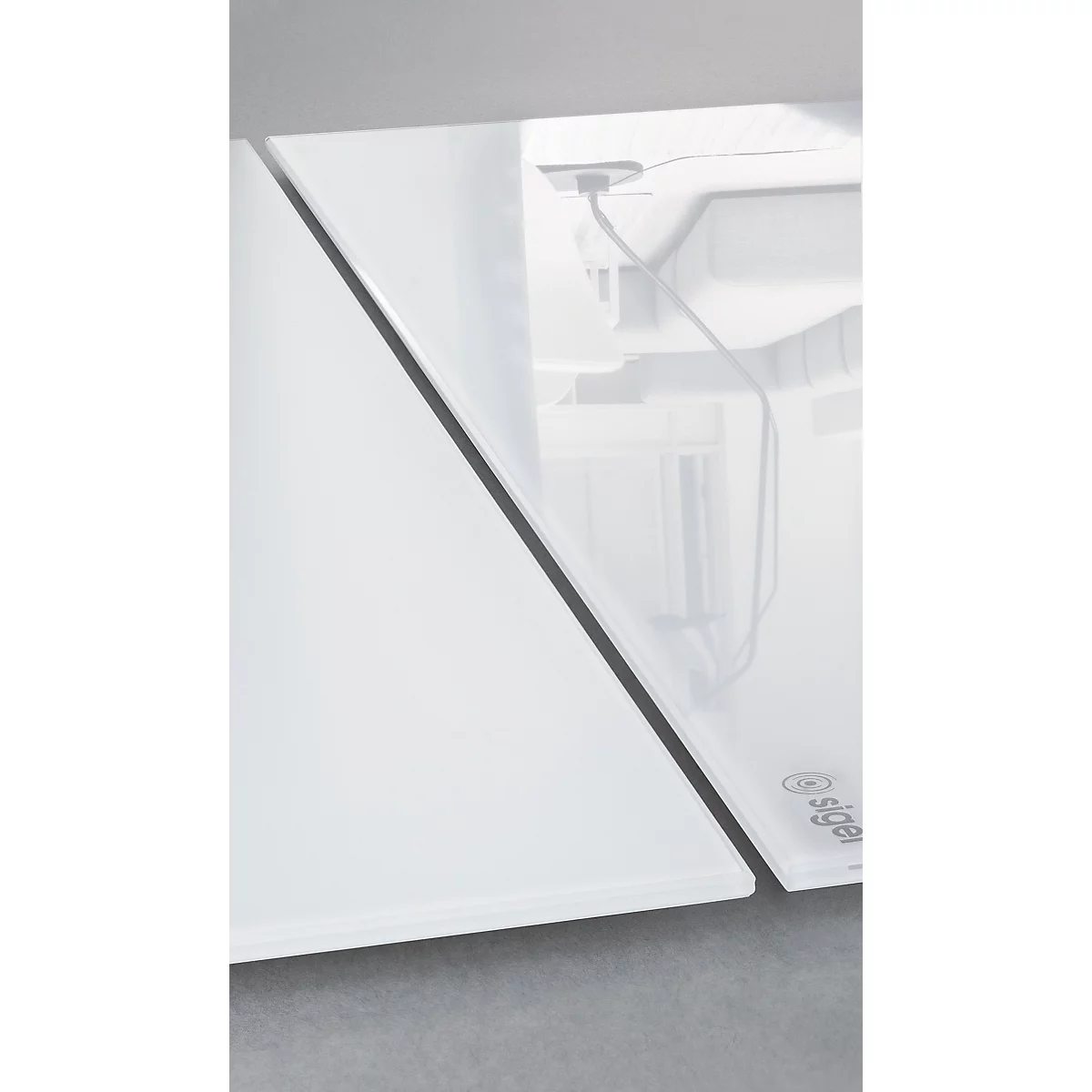 Deux surfaces rectangulaires blanches, séparées par une ligne noire, avec une vue sur les détails techniques en arrière-plan.