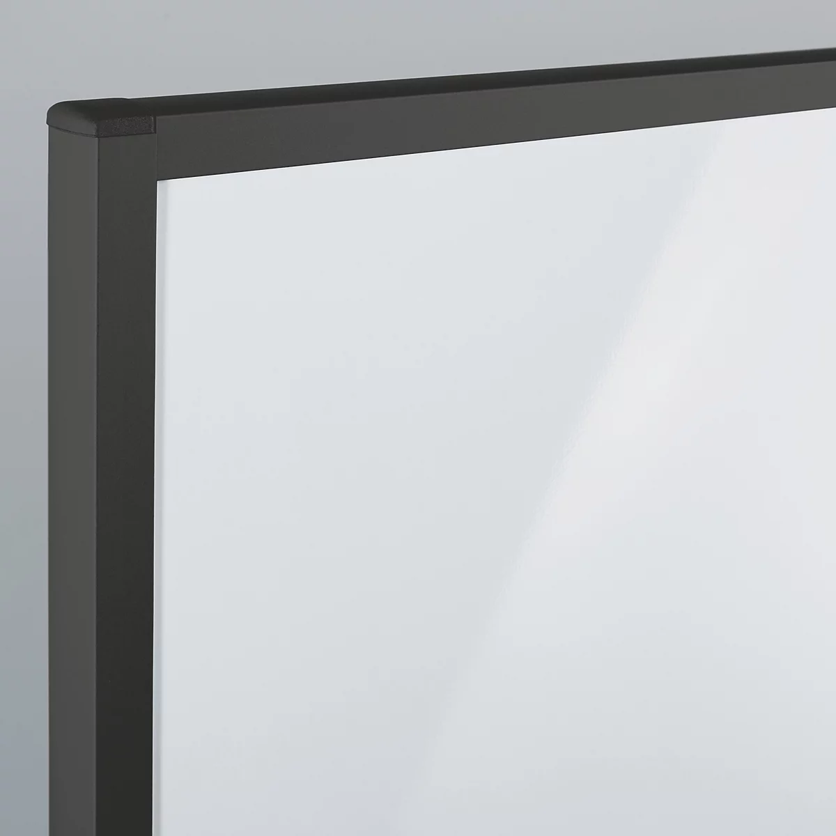 Detailansicht einer Ecke eines Whiteboards mit schwarzem Metallrahmen und weißer Schreibfläche.