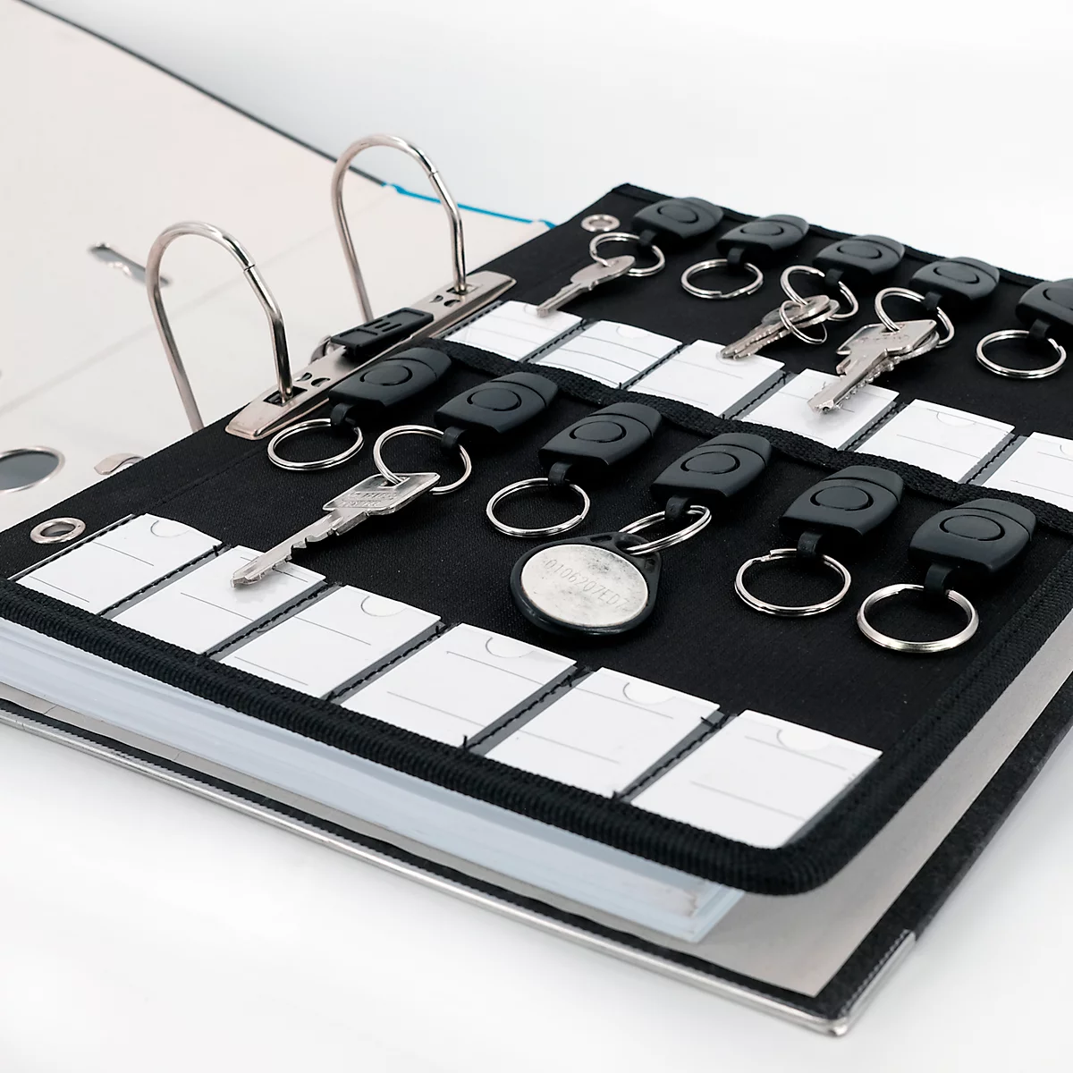 Een zwarte ringband met sleutelhangers. Sleutels en elektronische sleutels zijn ondergebracht in de houder.