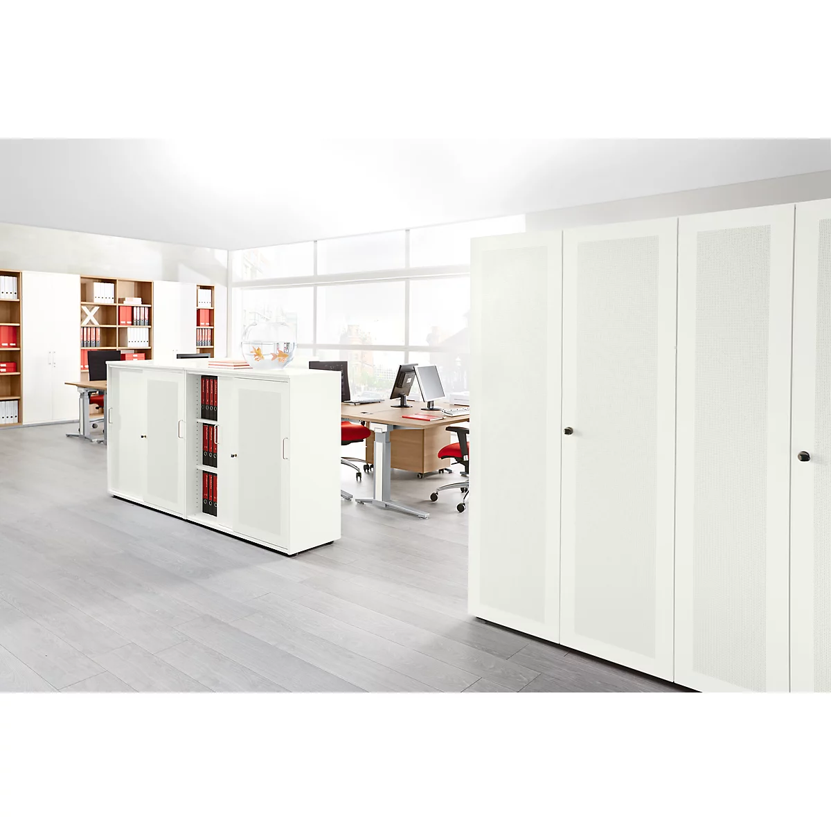 Bright office with cabinets, desks and chairs. Large windows illuminate the room. Files in the cabinets.