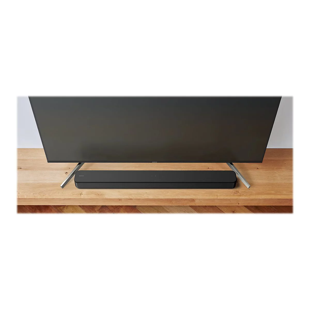 Ein Fernseher mit einer Soundbar vor einem Holz-Hintergrund.
