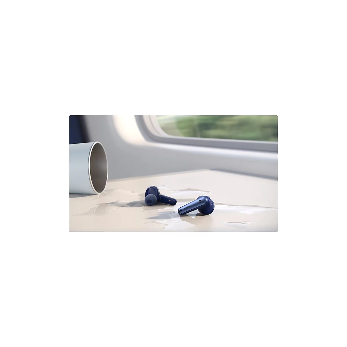 Blaue kabellose Ohrhörer liegen auf einer nassen Oberfläche neben einer umgestürzten Tasse.