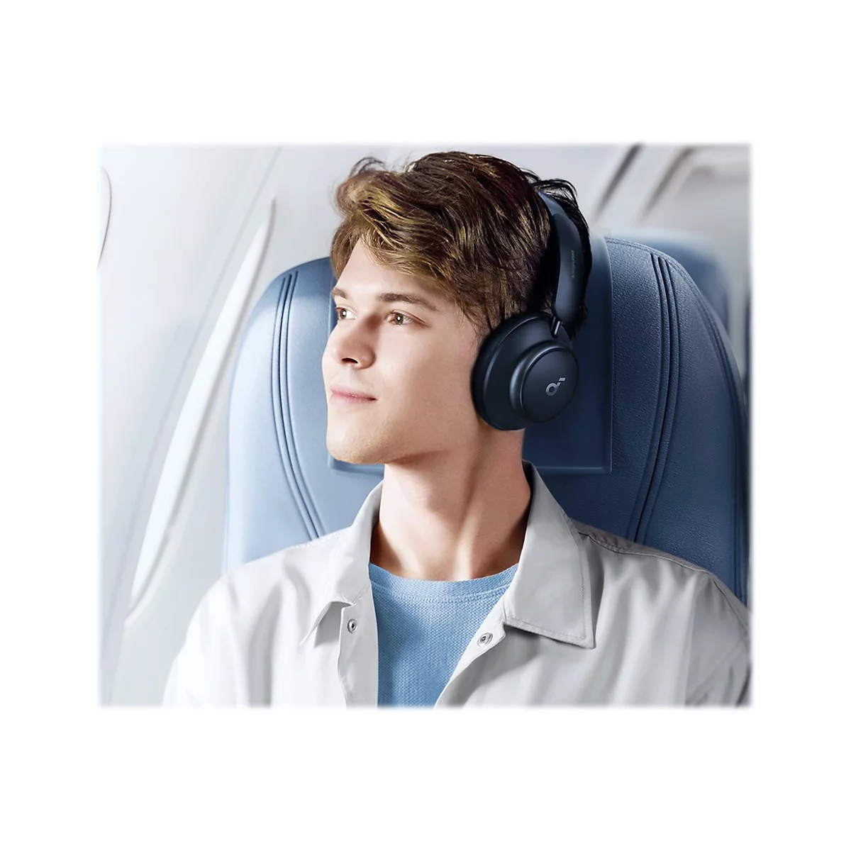 Ein Mann im Flugzeug mit KopfhÃ¶rern auf dem Kopf, schaut aus dem Fenster.