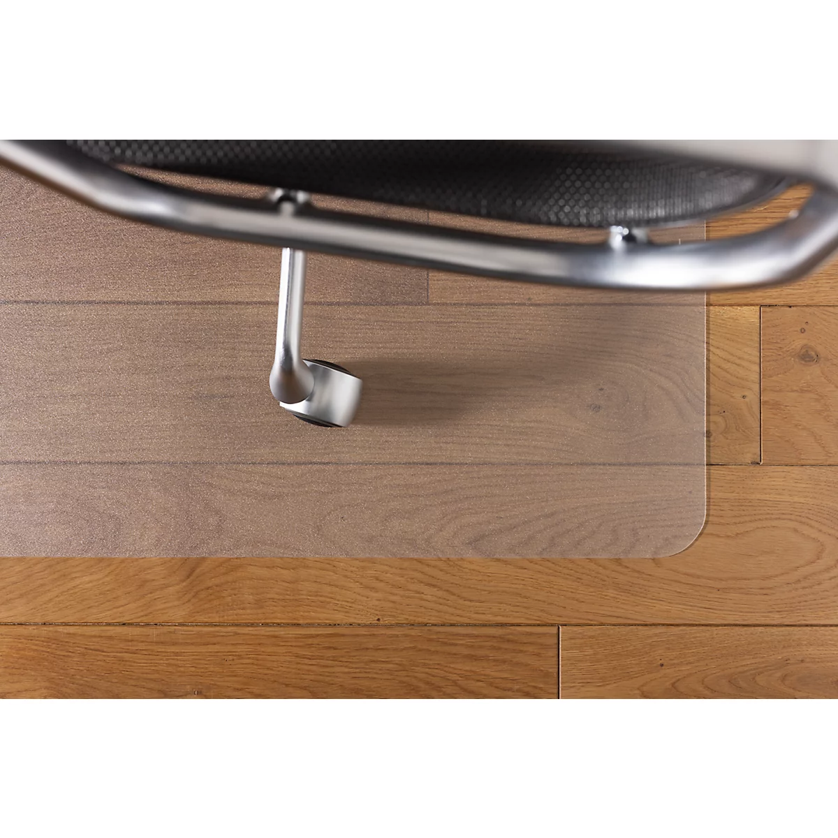 Pied de chaise de bureau avec roulette sur protège-sol transparent, sol en bois en dessous.