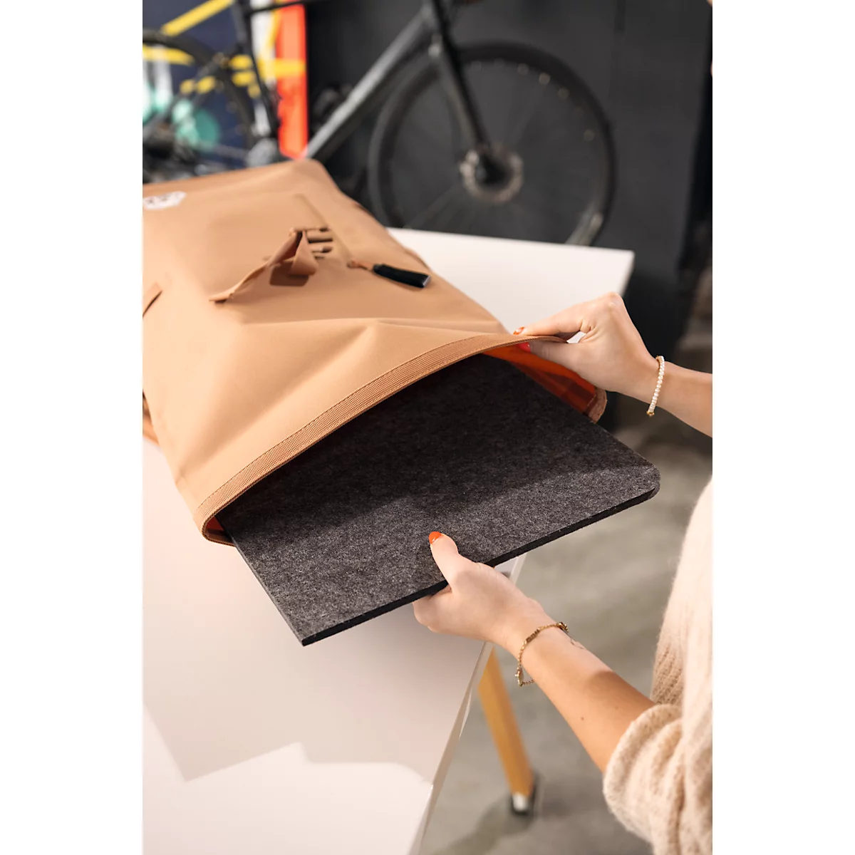 Personne ouvrant un sac et retirant une plaque de feutre grise. Un vélo et une table sont visibles en arrière-plan.