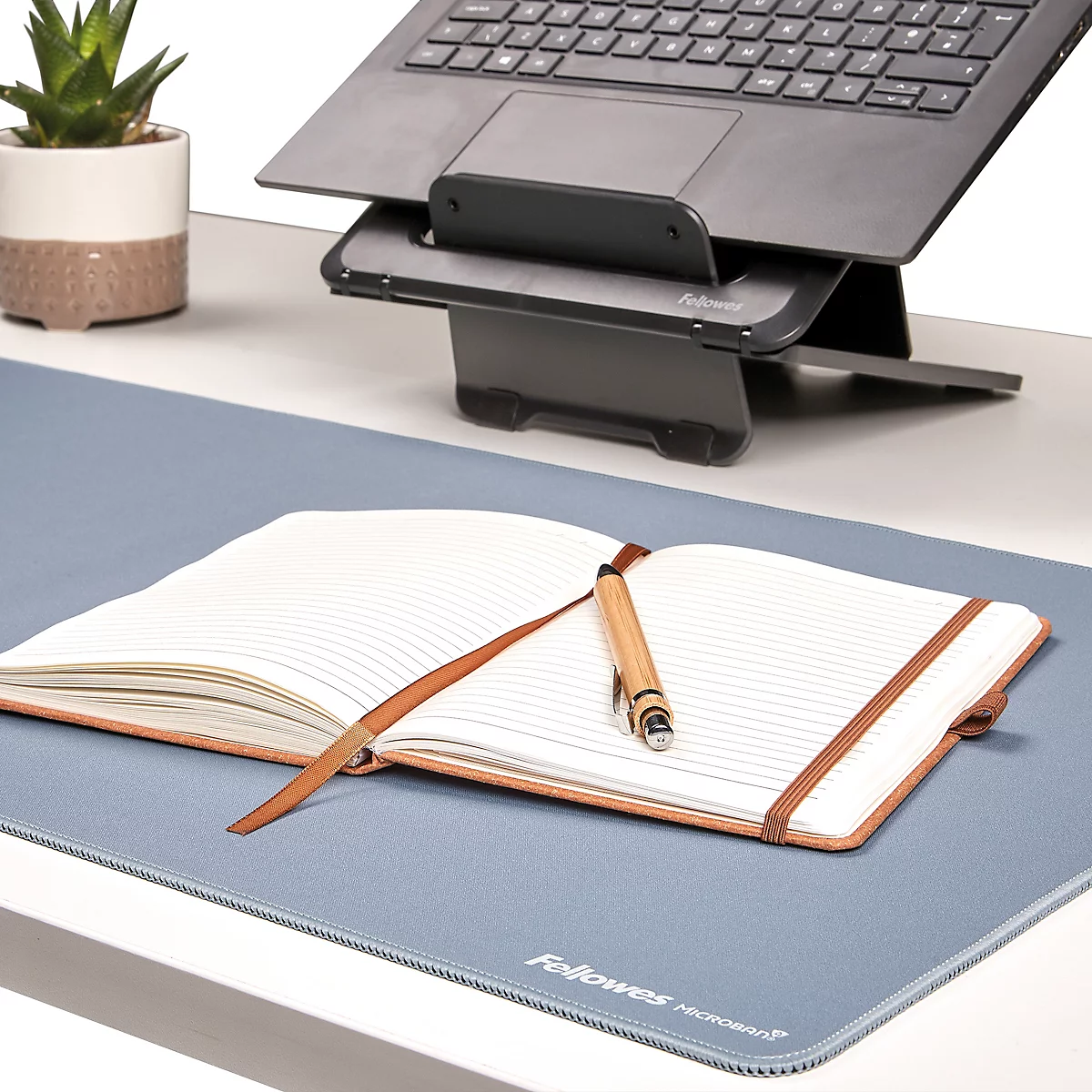 Tapis de bureau roulés en noir, gris, beige, vert et bleu. Le nom "Fellowes" est visible sur chaque tapis.