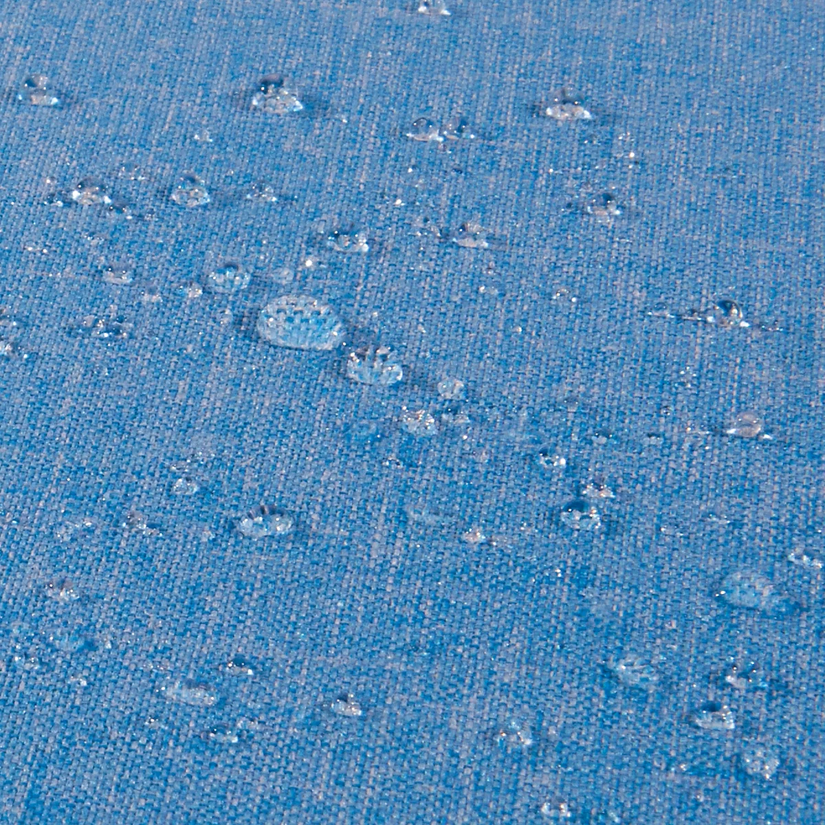 Gros plan sur un tissu bleu avec des gouttelettes d'eau qui s'accumulent dessus.