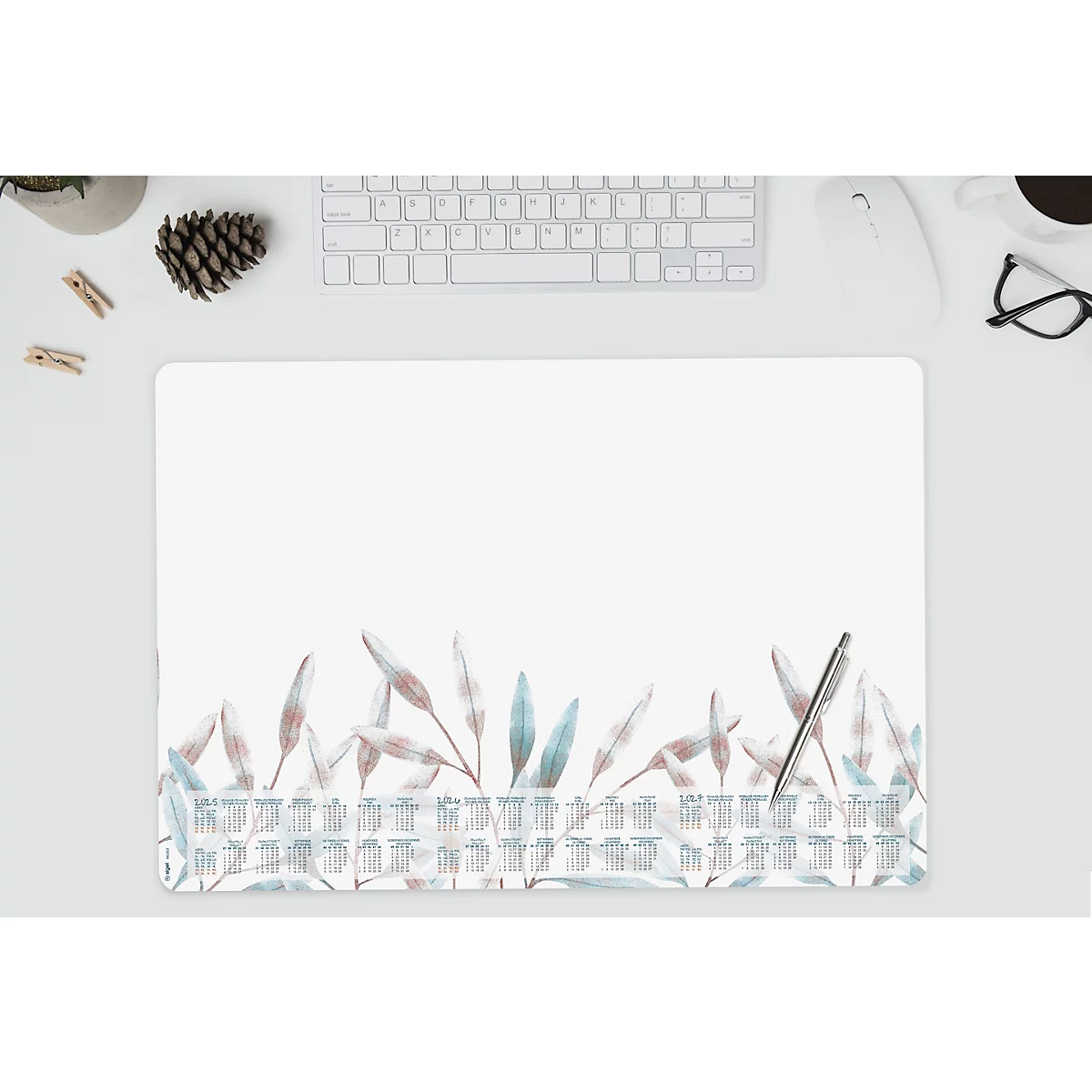 Tapis de bureau avec des feuilles bleu-beige, un clavier, un stylo et des accessoires. Ambiance lumineuse et aérée.