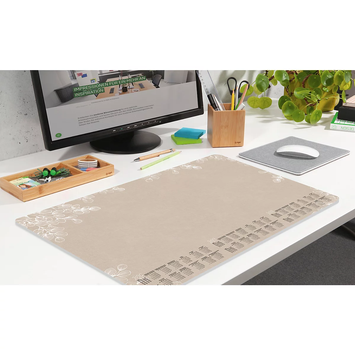Tapis de bureau beige avec fournitures de bureau telles que stylos, souris, moniteur, porte-stylos et petites plantes.