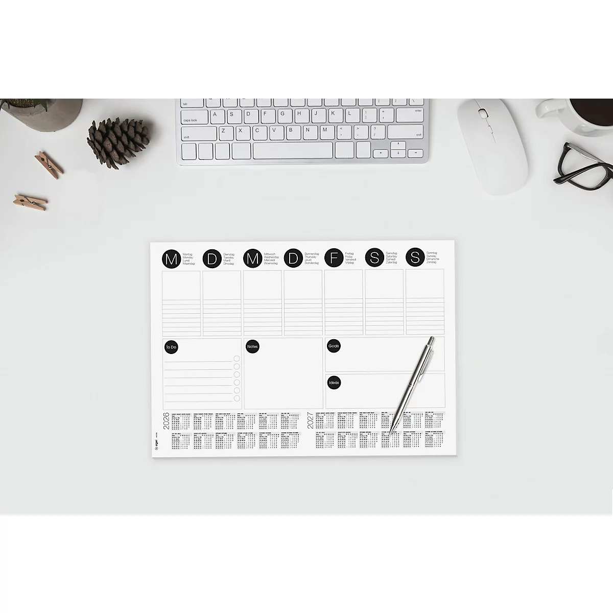 Vue de dessus d'un planificateur hebdomadaire avec un stylo sur un bureau blanc.