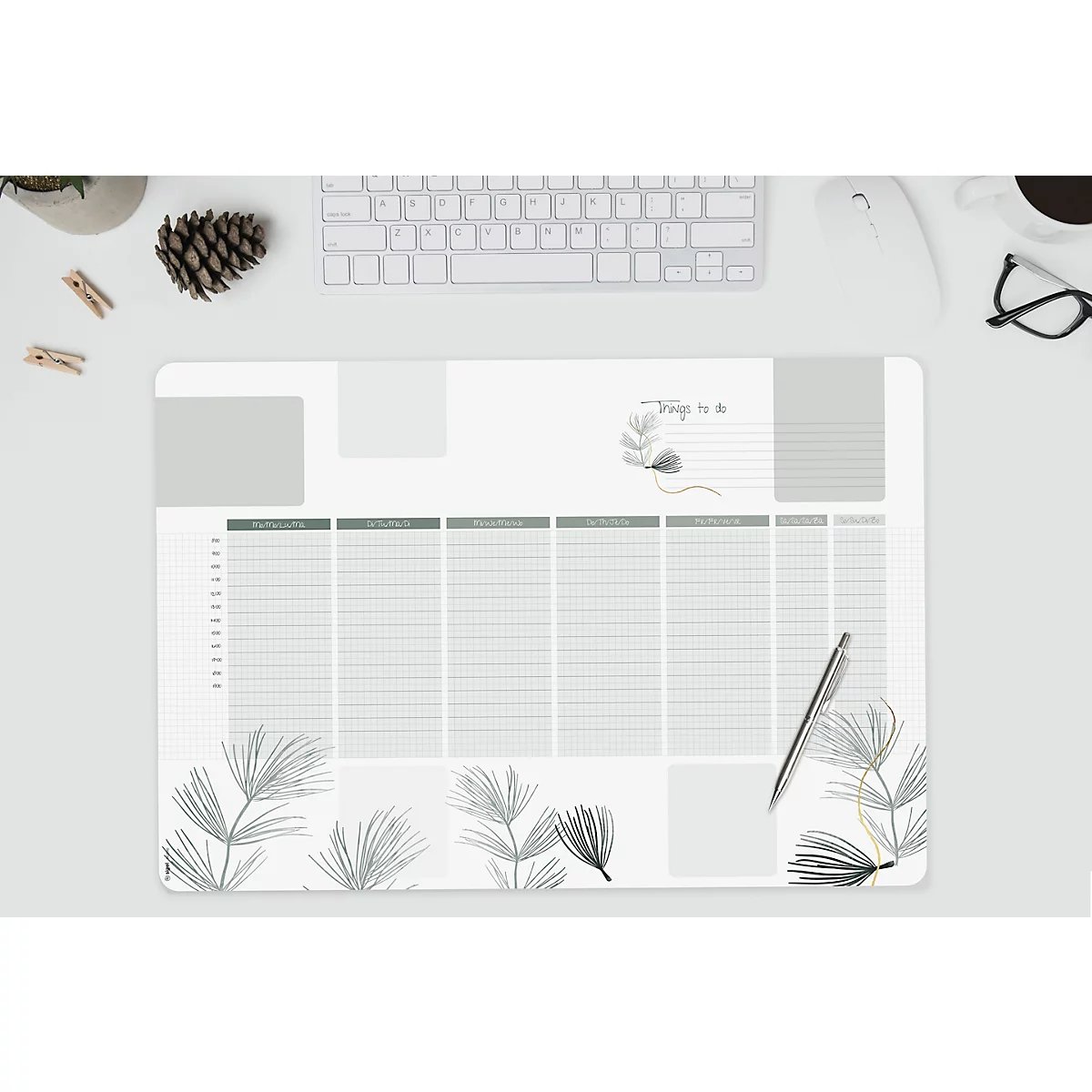 Tapis de bureau avec un planificateur hebdomadaire et des éléments floraux. Stylo, clavier et autres accessoires sont sur la table.