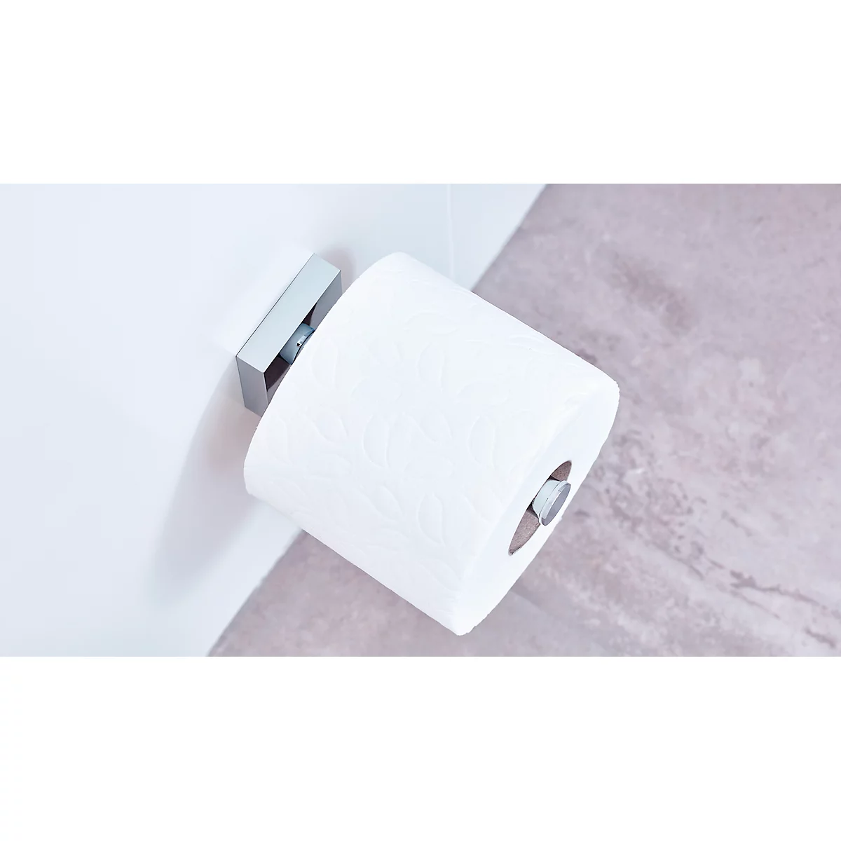 White toilet paper hanging on a silver holder on the wall. A marbled surface can be seen in the background.