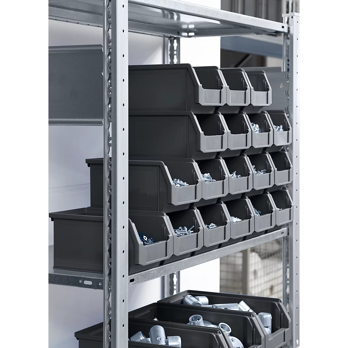 Étagère métallique grise avec de nombreux bacs en plastique gris remplis de petites pièces.