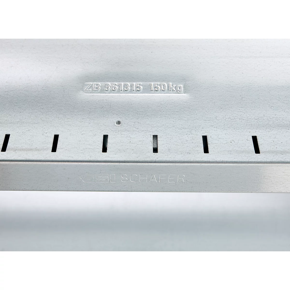 Close-up of a silver metal part with cutouts and lettering. Top: "ZB 951815 150 kg"; Bottom: "KOCH & SCHÄFER"