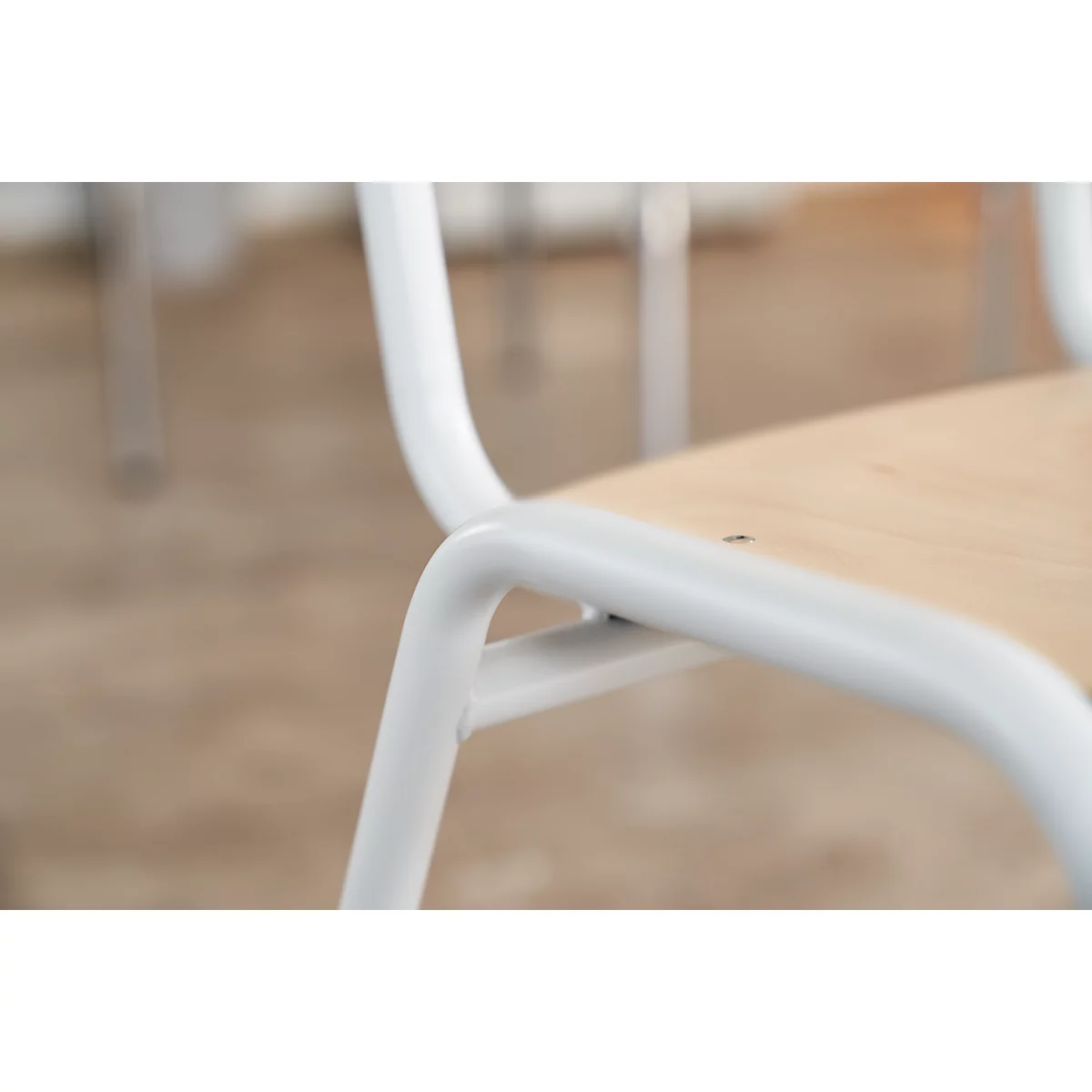 Close-up of a white metal chair with wooden seat.