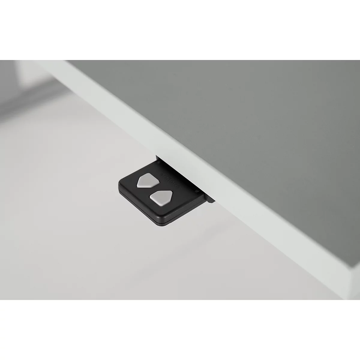 Close-up of a table top and a black control unit with silver arrow keys.