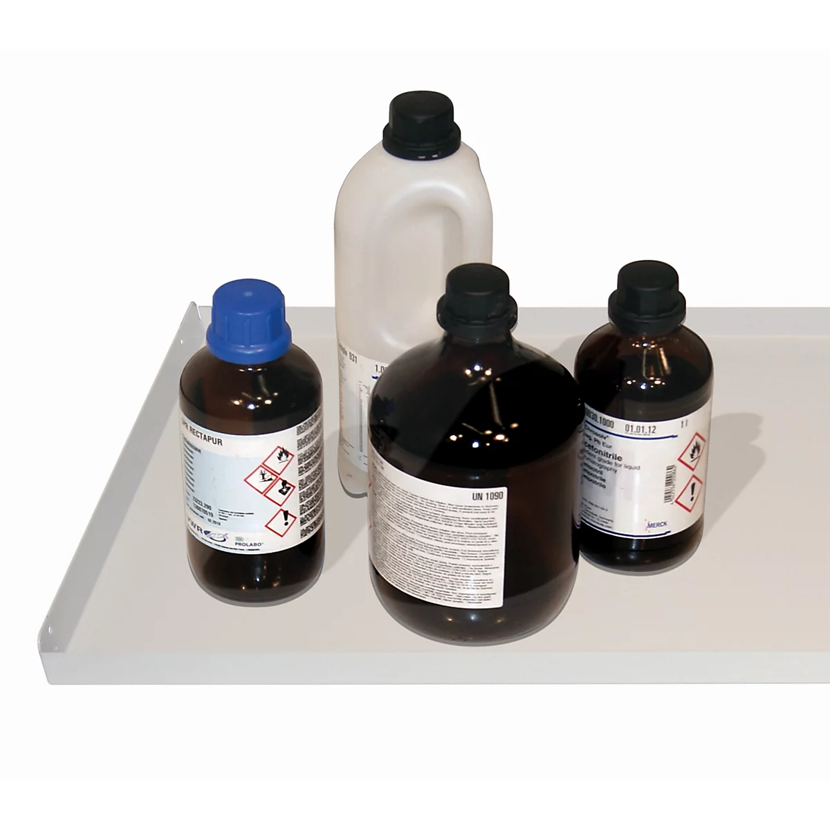 Four chemical bottles on a white tray. Two brown bottles and a light bottle with a handle. All have black lids.