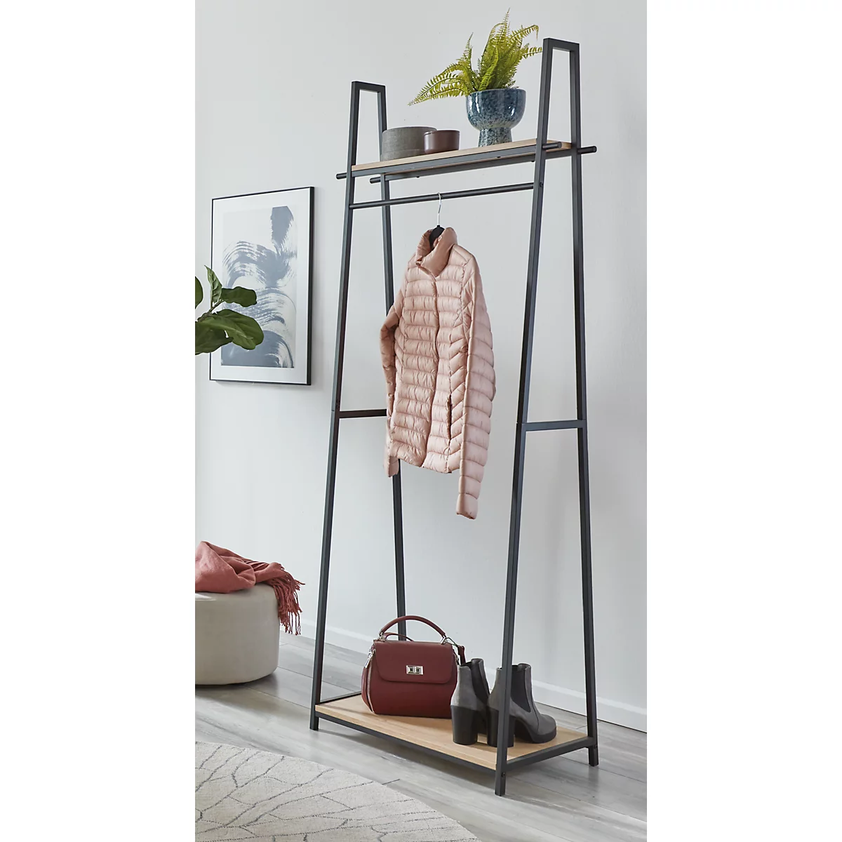 Eine Garderobe in Schwarz mit Ablageflächen. Jacke, Tasche und Schuhe dekoriert die Ablage.