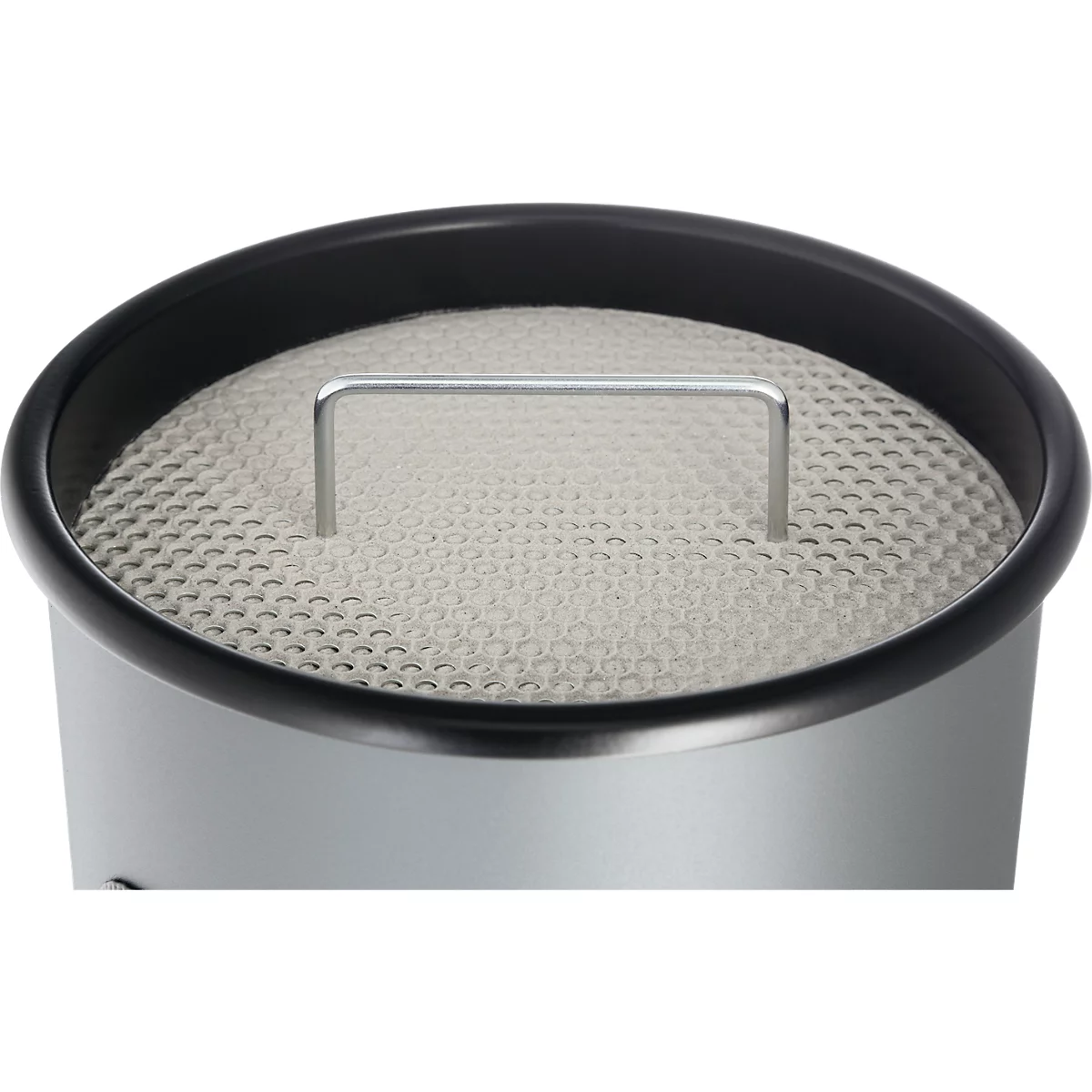 Close-up of a silver container with a perforated beige filter insert and a small metal handle.