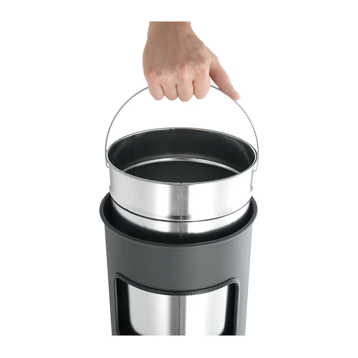 A hand holds a metal bucket, which is inserted into a dark, cylindrical container.