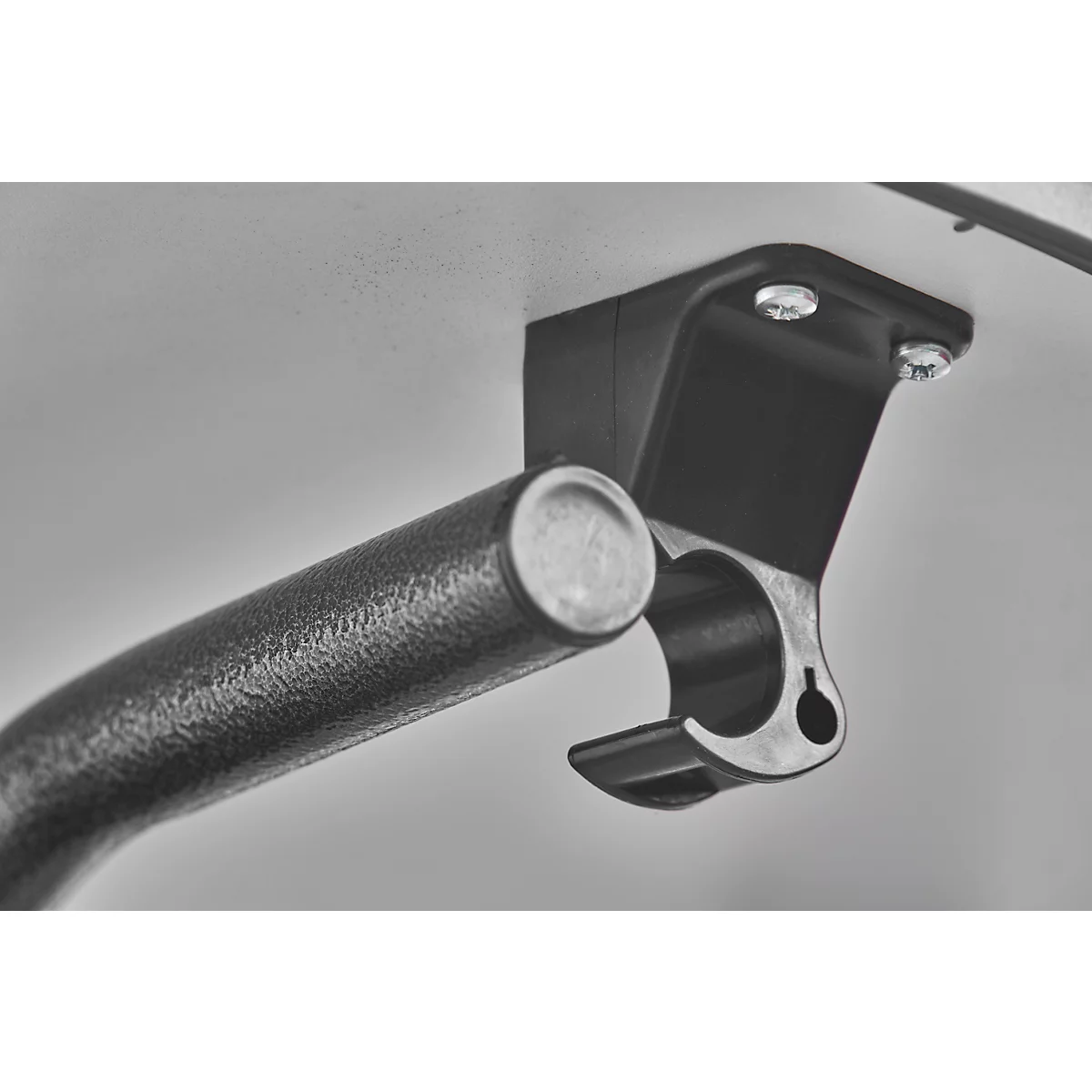 Close-up of a bracket with a metal bar. The bracket is attached to a gray surface, metal bar in the bracket.