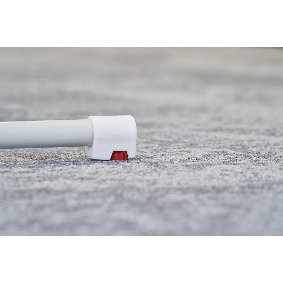 Close-up of a white product detail with a red element on a gray, textured background.