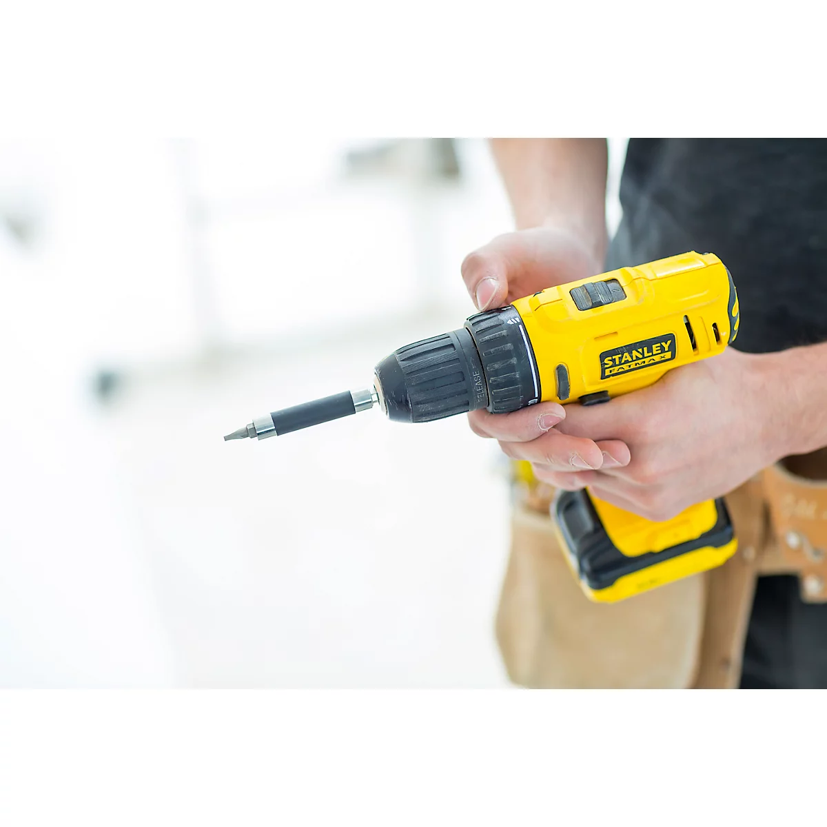 Person holding a yellow cordless drill. A screw attachment extends from the device.