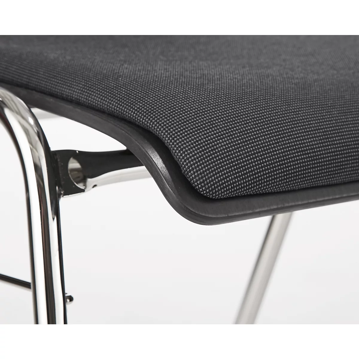 Close-up van een stoelzitting met zwarte stof, ondersteund door een metalen frame.