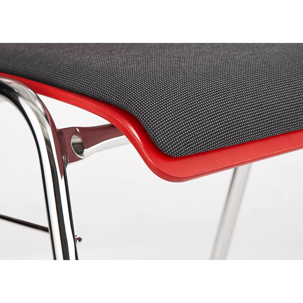 Detailopname van een stoel. Rode frame omsluit een grijze zitting, chromen poten.