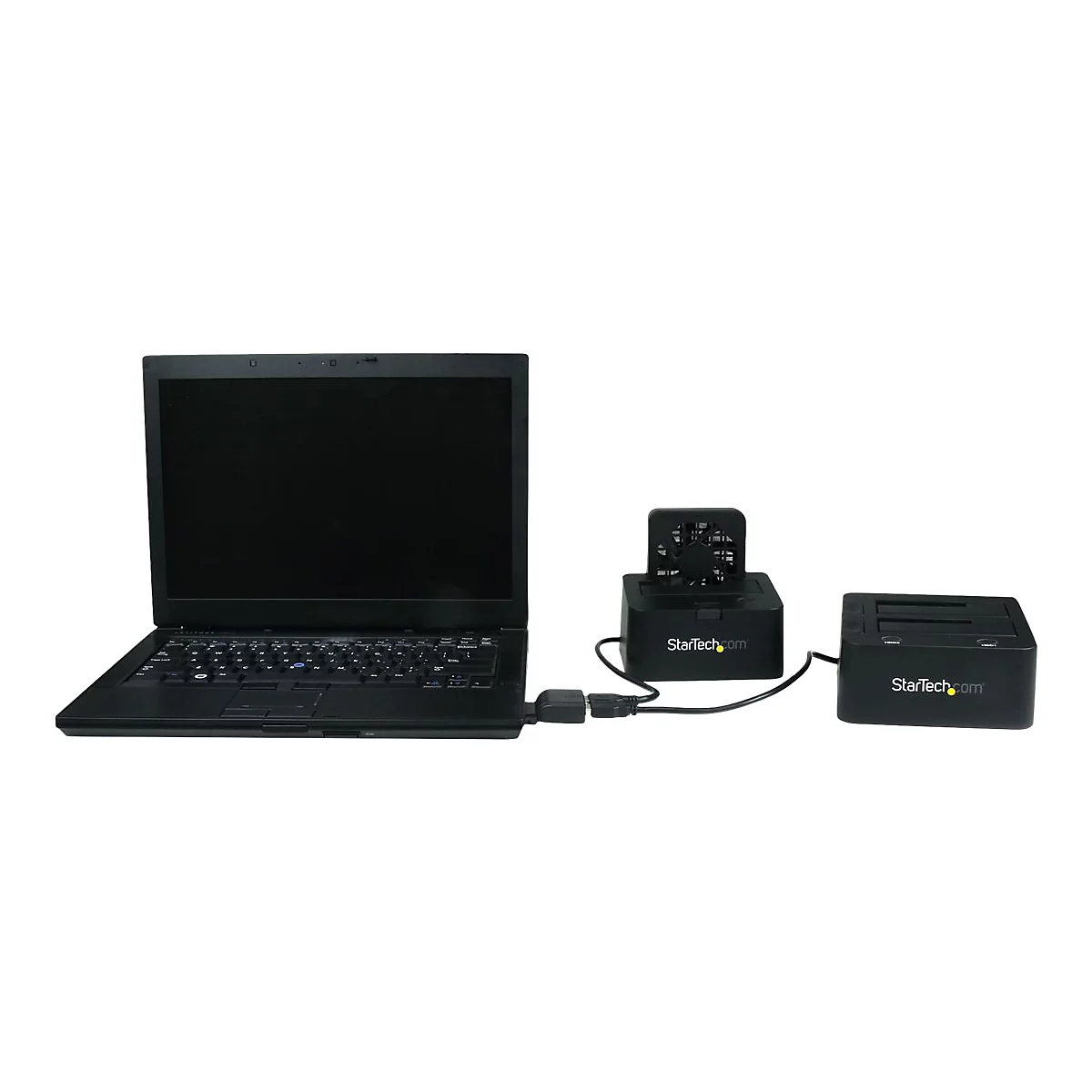 Un ordinateur portable noir connecté à deux stations d'accueil pour disque dur noires avec le logo StarTech.com. Le tout sur fond blanc.