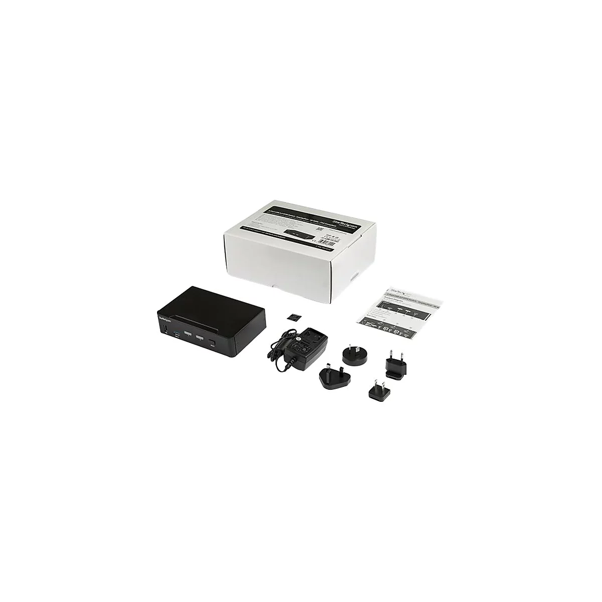 Appareil noir avec des accessoires tels qu'un adaptateur secteur, des cÃ¢bles et des manuels sur fond blanc. L'emballage est Ã©galement visible.