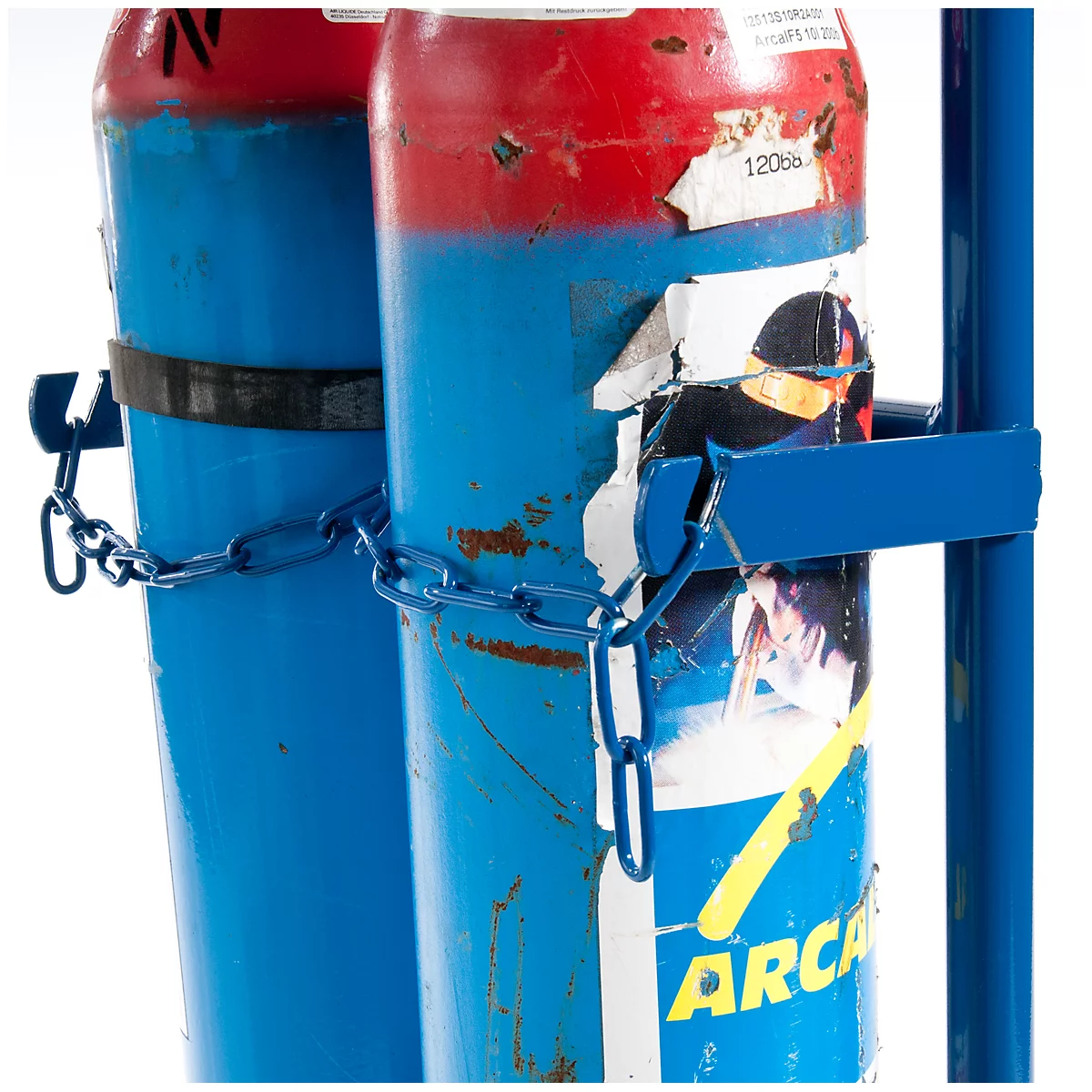 Two blue gas cylinders, red at the top, secured with stickers and chains. A blue holder keeps them together.