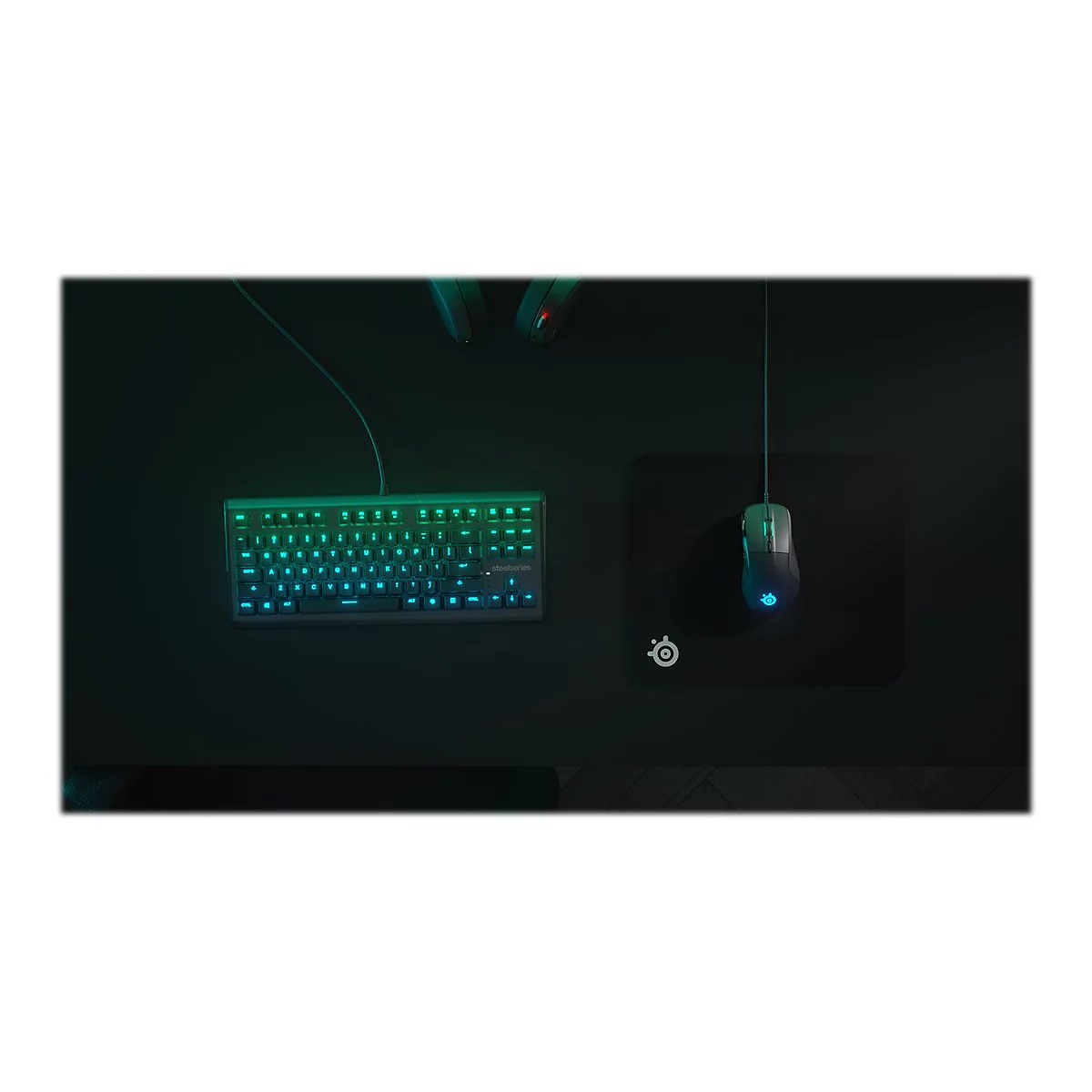 Draufsicht auf Gaming-Zubehör: Tastatur mit blauer Beleuchtung, Maus auf Mauspad.
