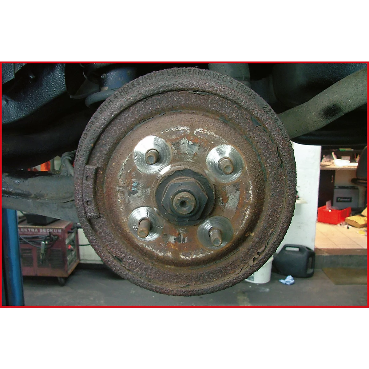 Nahaufnahme einer verrosteten Fahrzeugbremstrommel mit Bolzen und Muttern. Der Rost bedeckt einen Großteil der Metalloberfläche.
