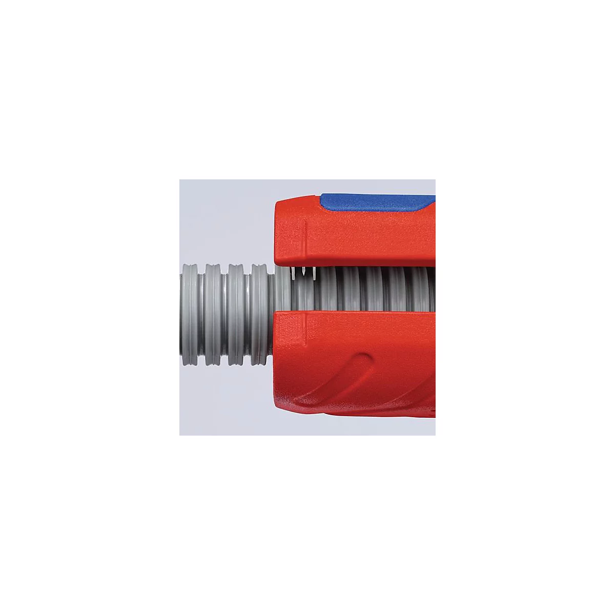 Close-up of tool: A red and blue wrench gripping a gray, corrugated pipe.