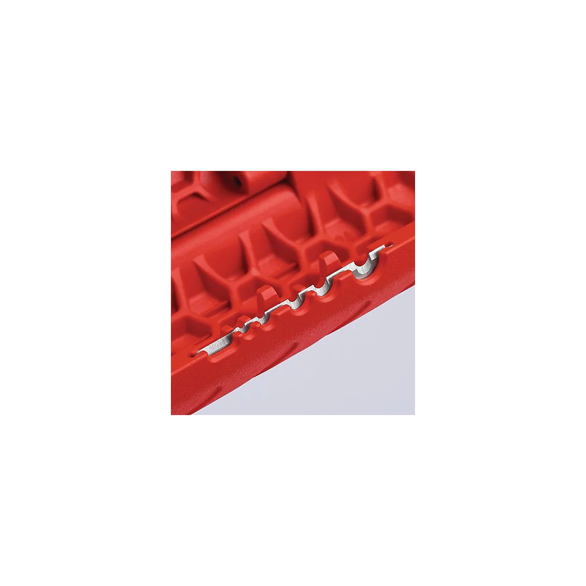 Close-up of a red tool with a silver cutting edge.