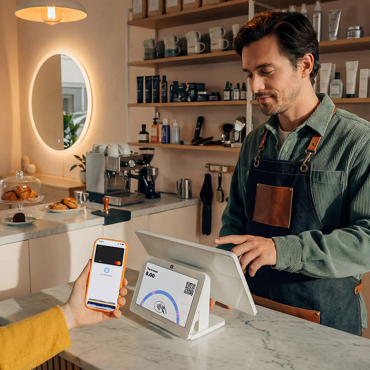 Ein Kunde bezahlt kontaktlos mit dem Smartphone an einem Kassenterminal in einem Café.