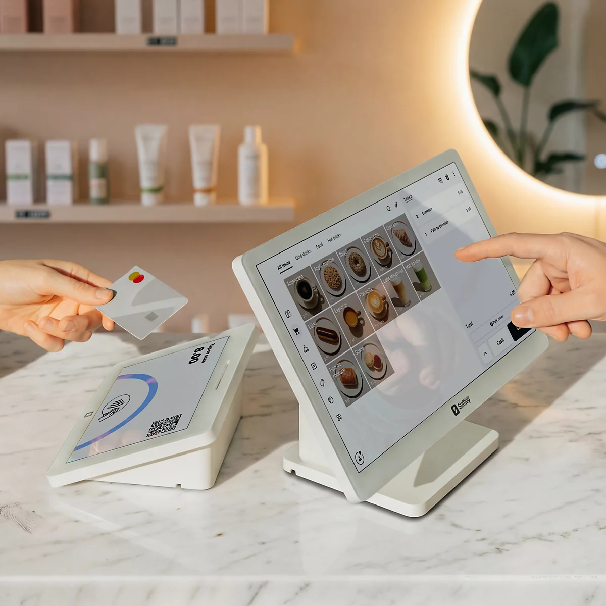 Ein Kassenterminal mit Touchscreen auf einem Marmortresen, während eine Karte kontaktlos an ein Lesegerät gehalten wird.