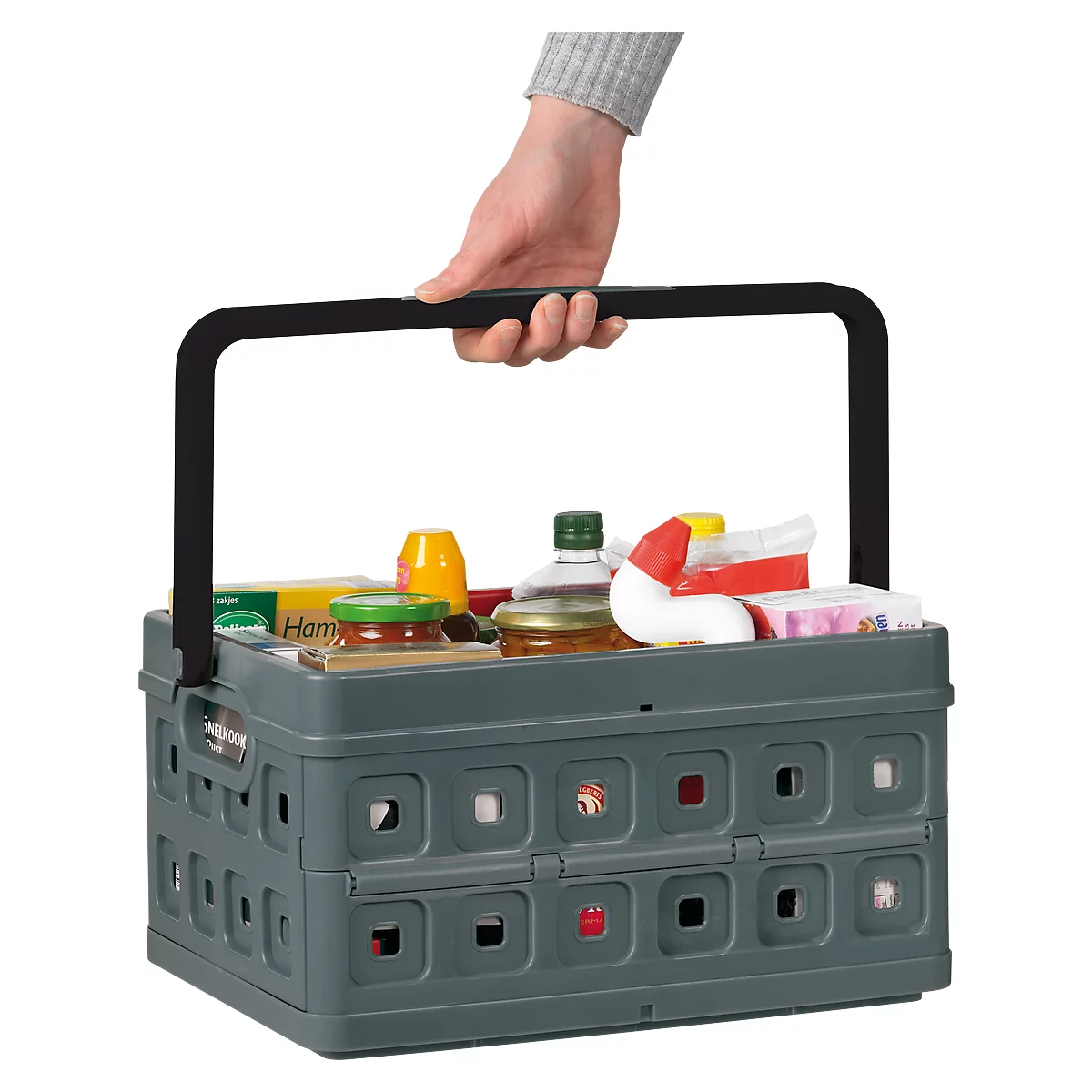 Person hält graue, zusammenklappbare Einkaufskiste mit Produkten. Schwarzer Griff. Kiste ist gefüllt mit Lebensmitteln, wie Senf, Marmelade und Öl.