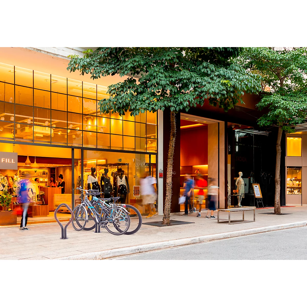 Entrée d'un magasin avec vitrines, personnes et vélos.